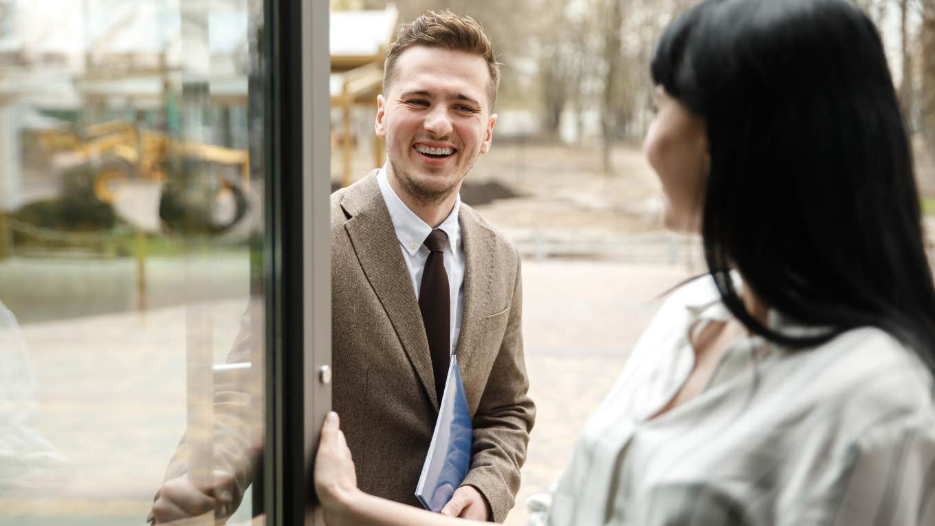 Things Men Notice About A Woman Within The First 30 Seconds, But Won't Admit woman holding door open for man who is looking at her smiling