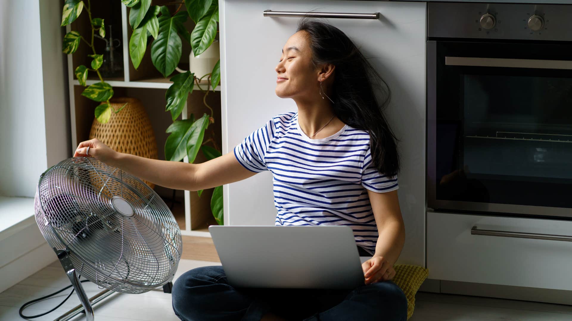 woman using a box fan to cool down