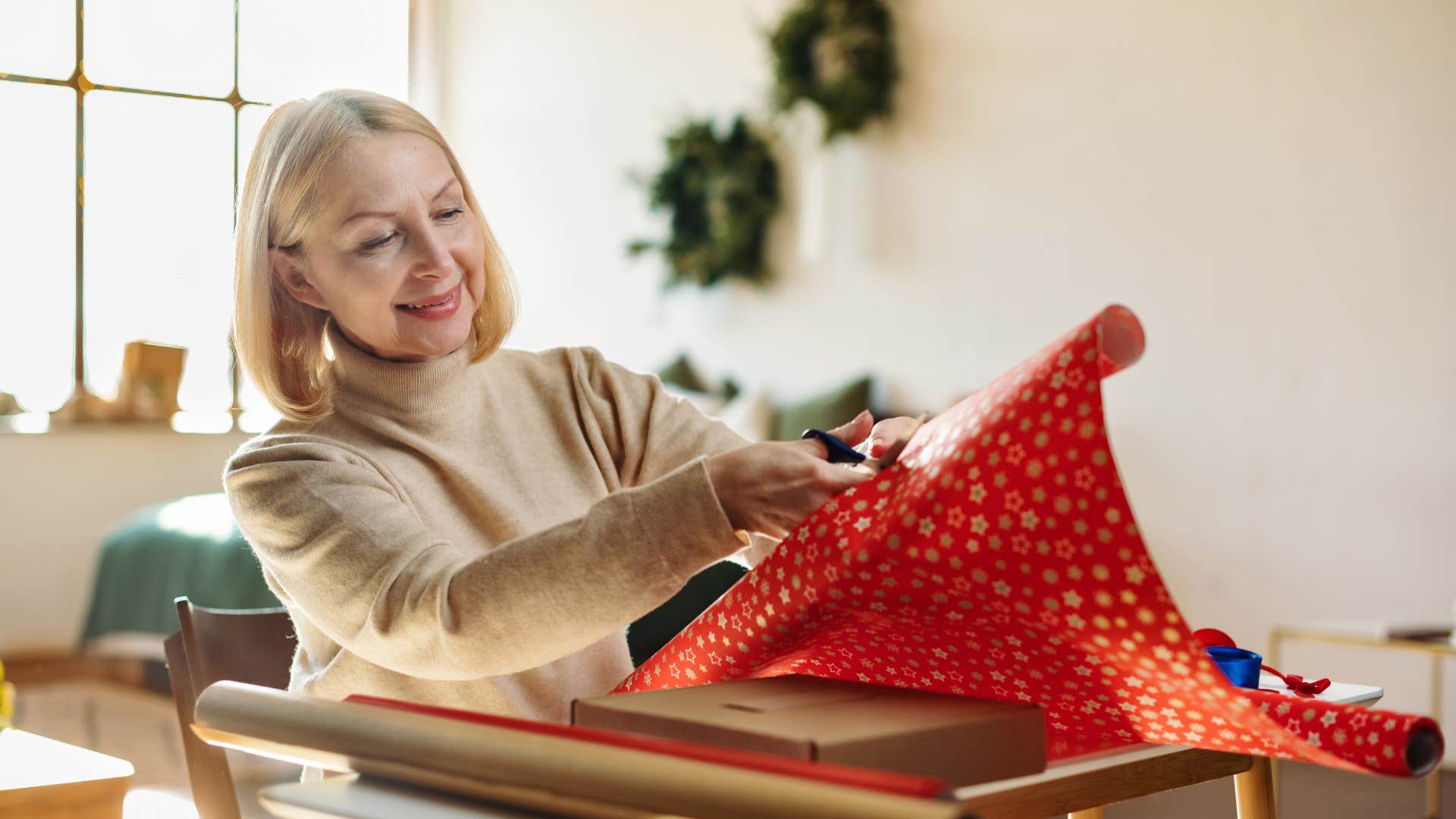 woman reusing gift wrap to wrap present