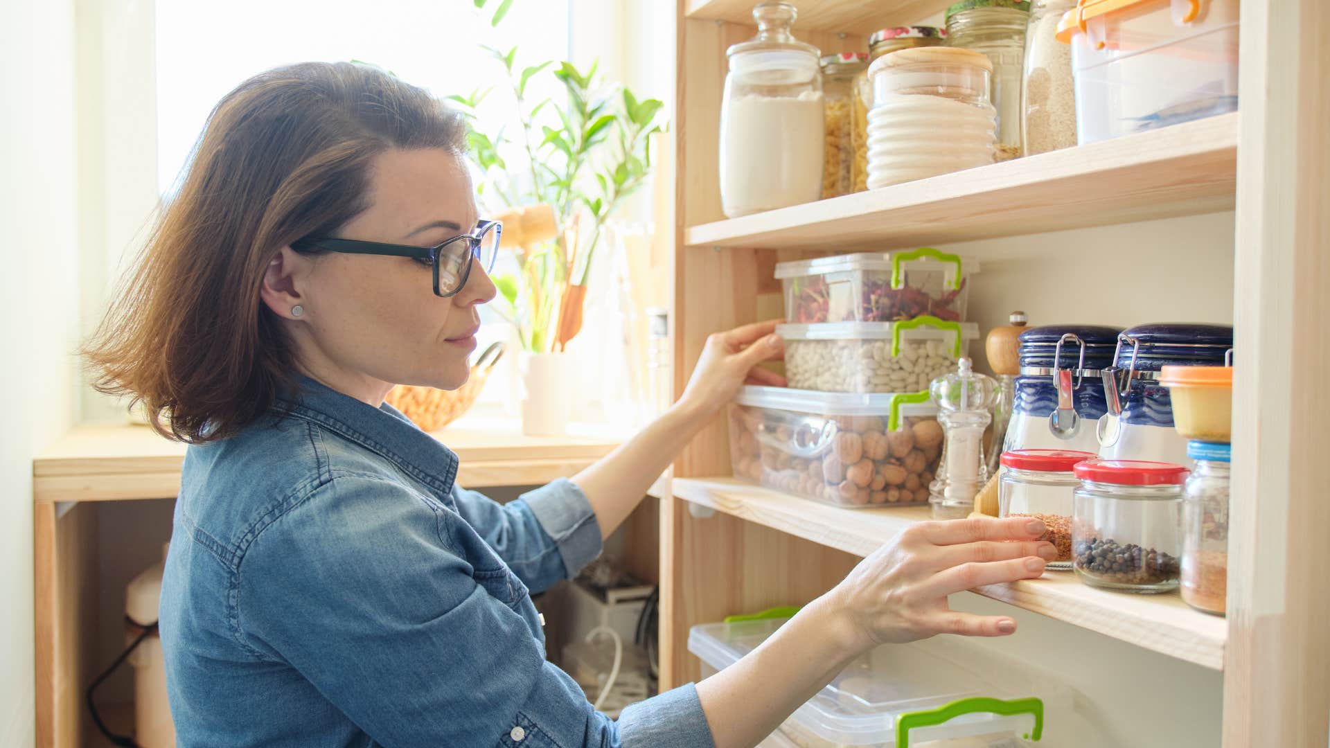 woman putting reused jars and food containers in the pantry