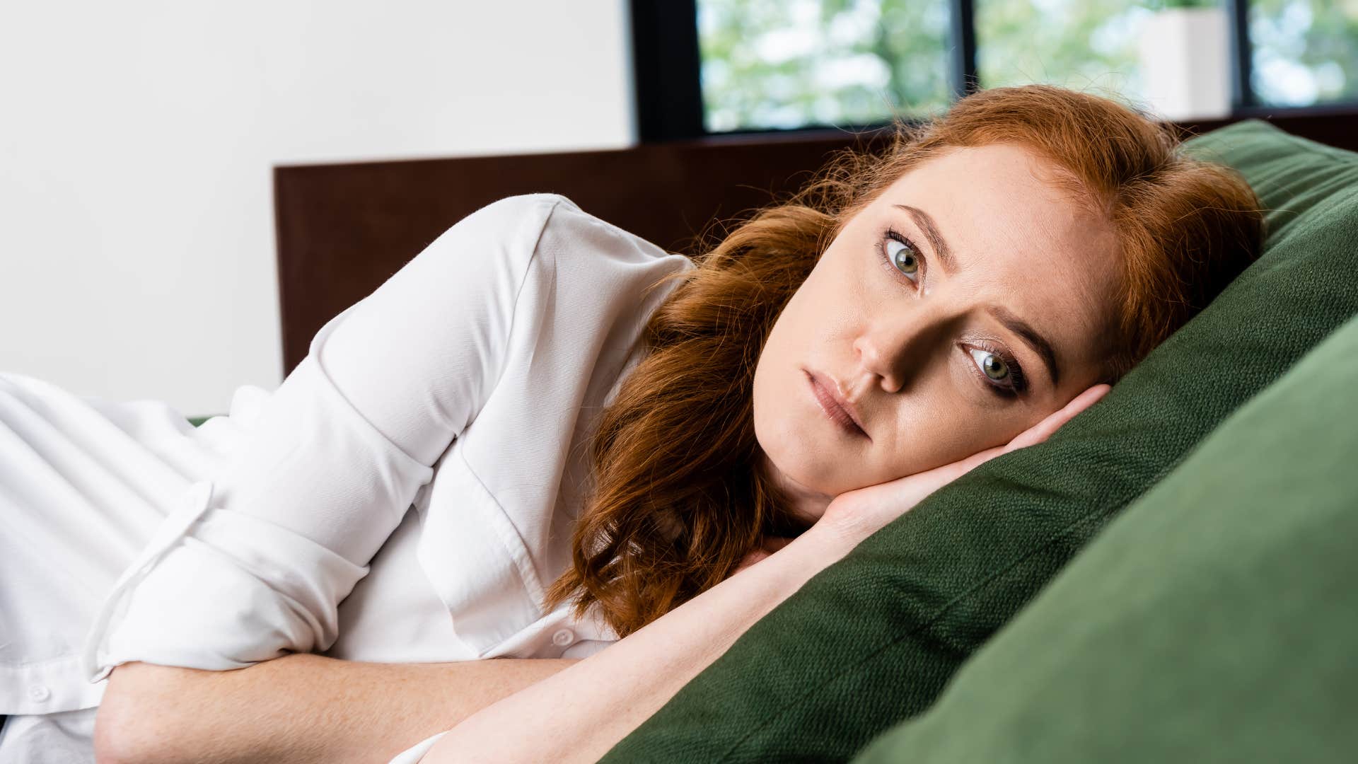 Woman feeling misunderstood and laying on her couch.