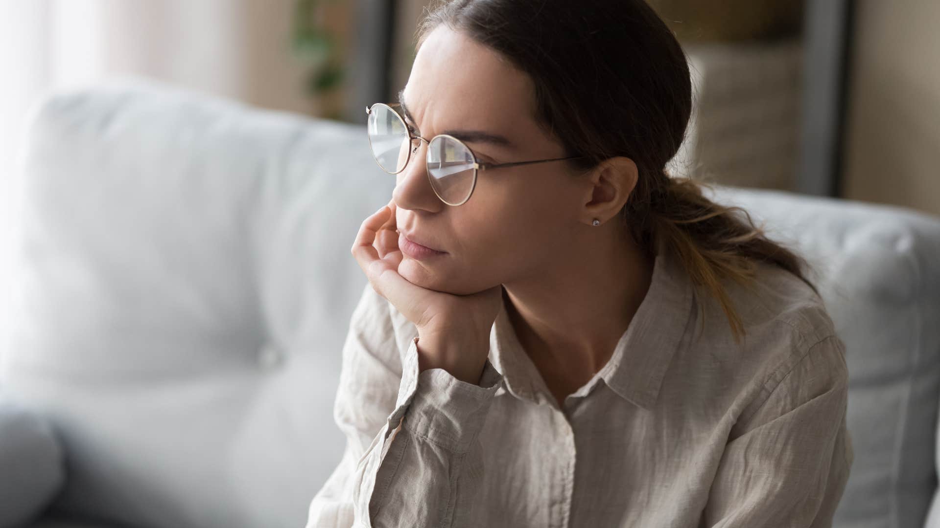 Woman suppressing emotions and sitting on her couch.