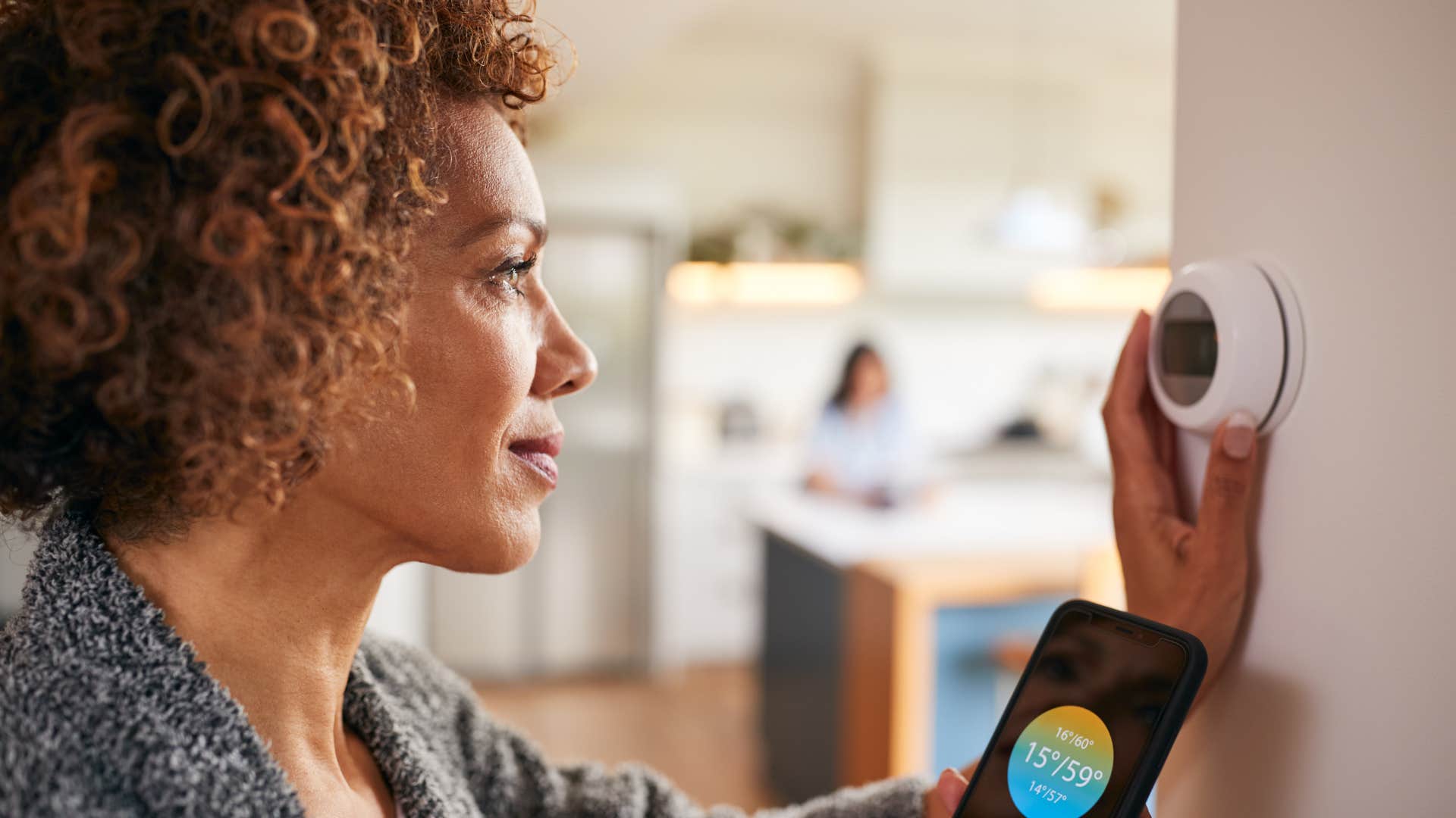 Woman using her smart home features on a thermostat.
