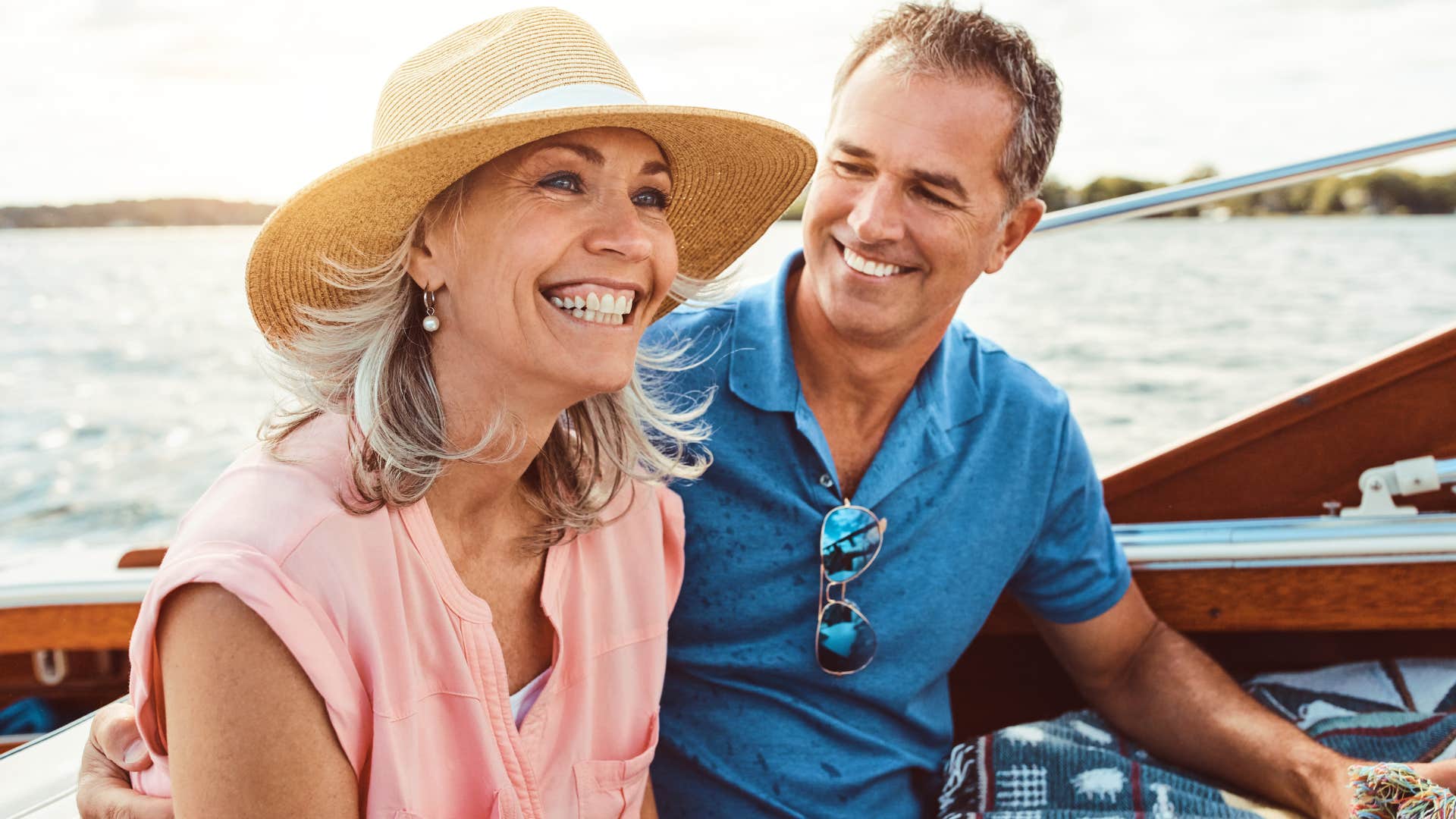 Couple who goes on multiple vacations a year smiling on a boat.