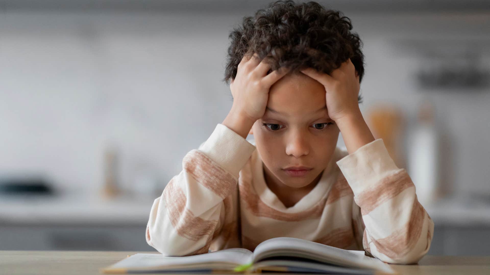 young boy feeling powerless sitting at table