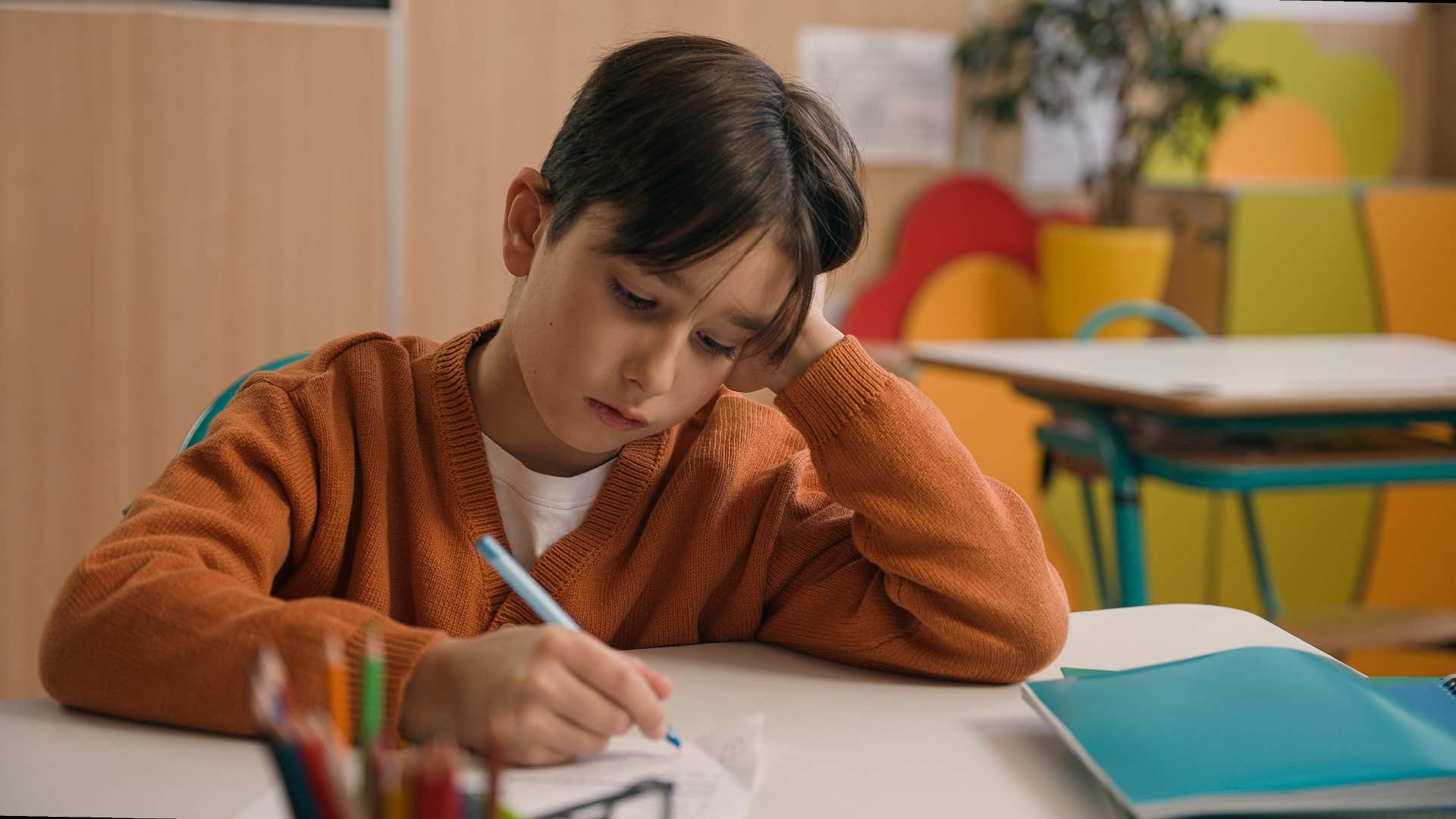 young boy thinking while doing work in class