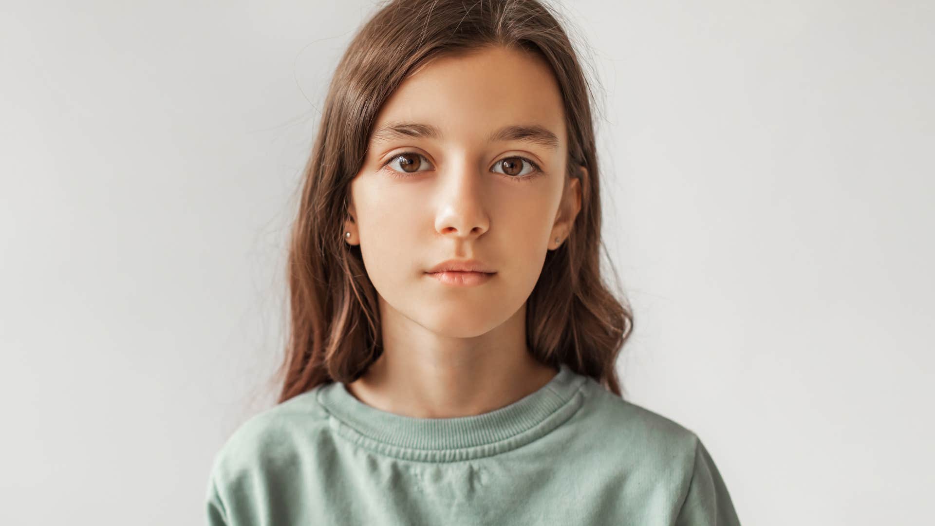 serious child standing against plain background
