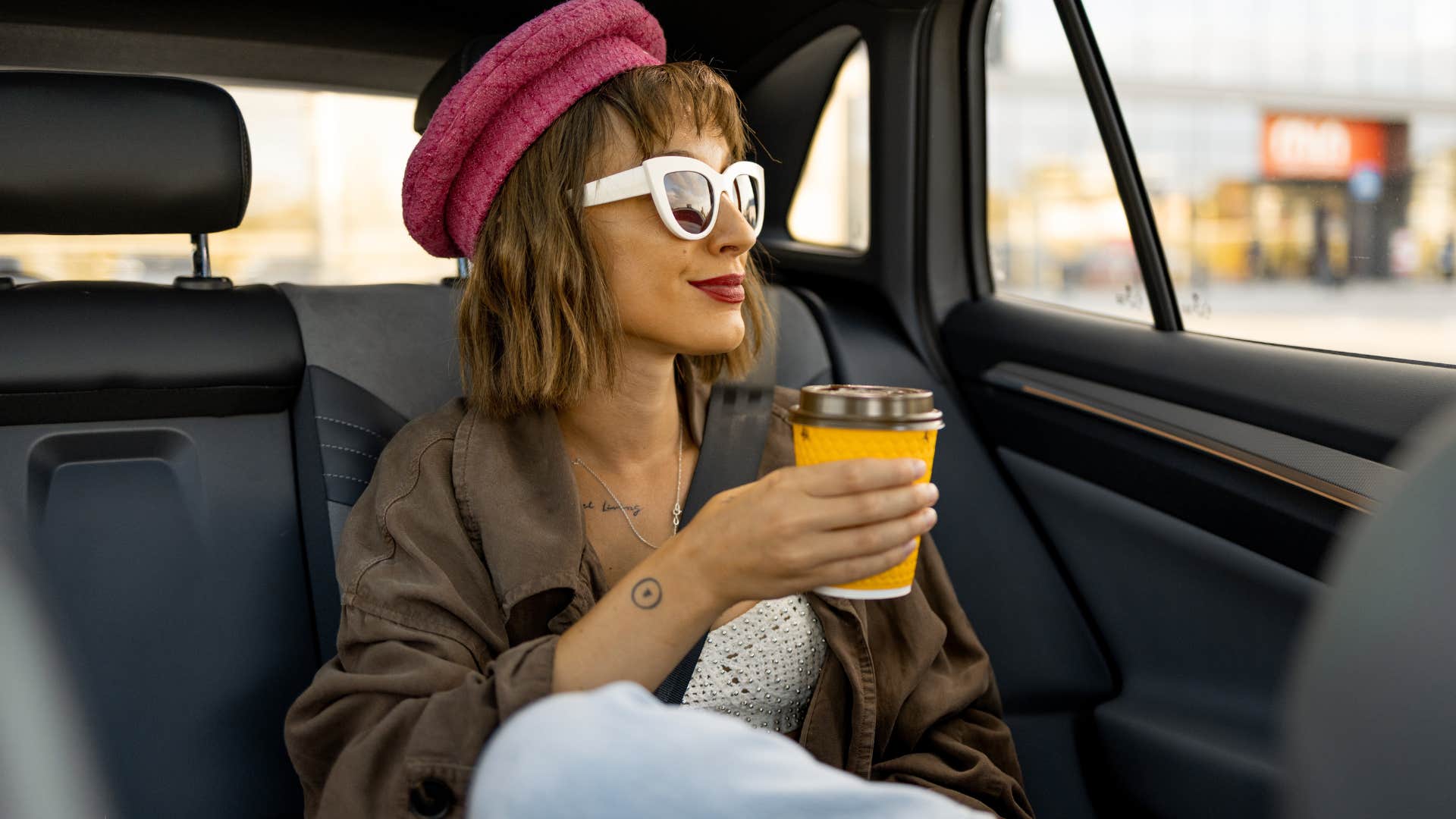 woman drinking coffee in the backseat of a car