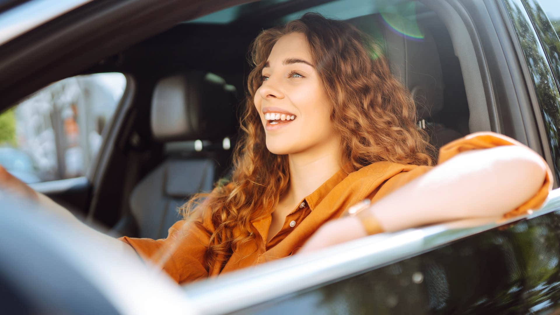 woman smiling and driving new car