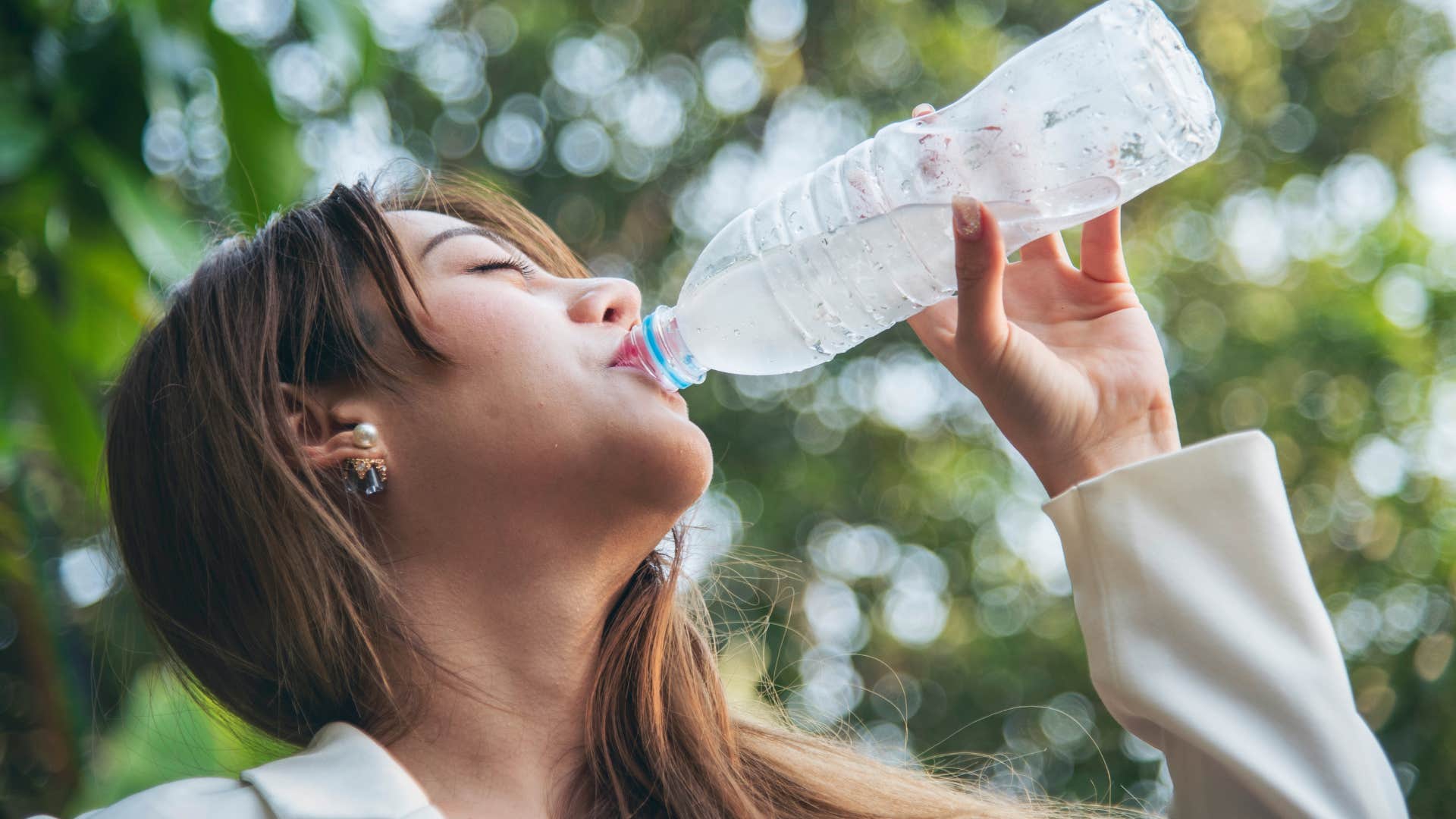 woman drinking from a single-use water bottle