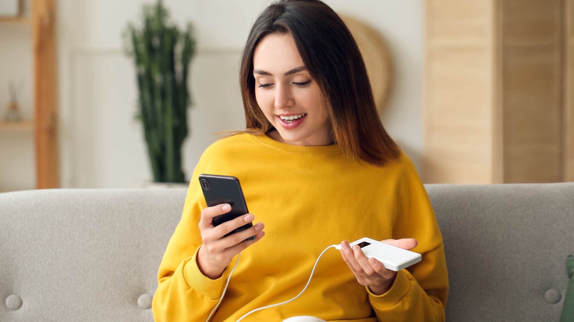 Woman holding her phone and old power cords at home.