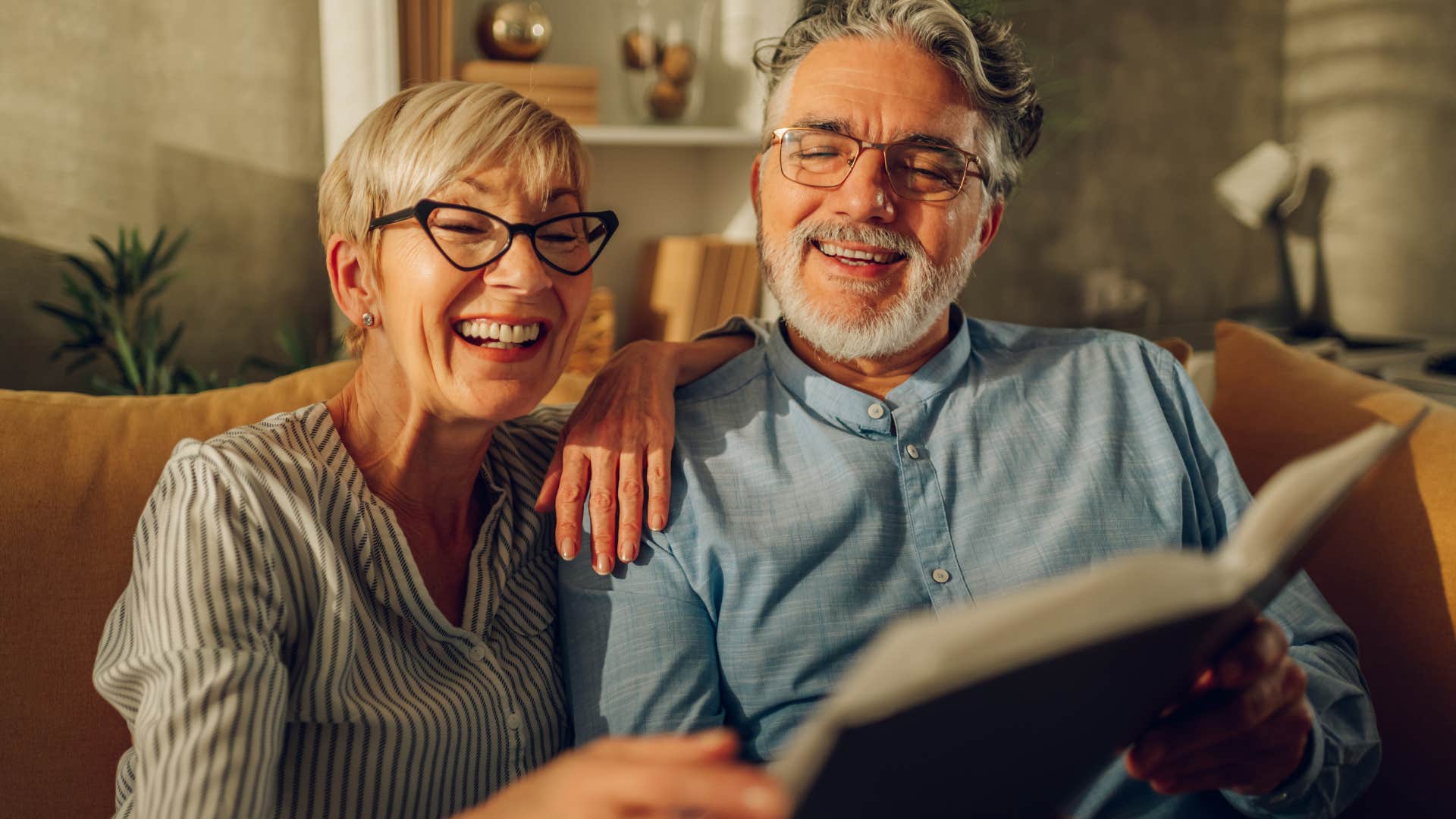Old couple smiling and looking at sentimental items for your kids at home.