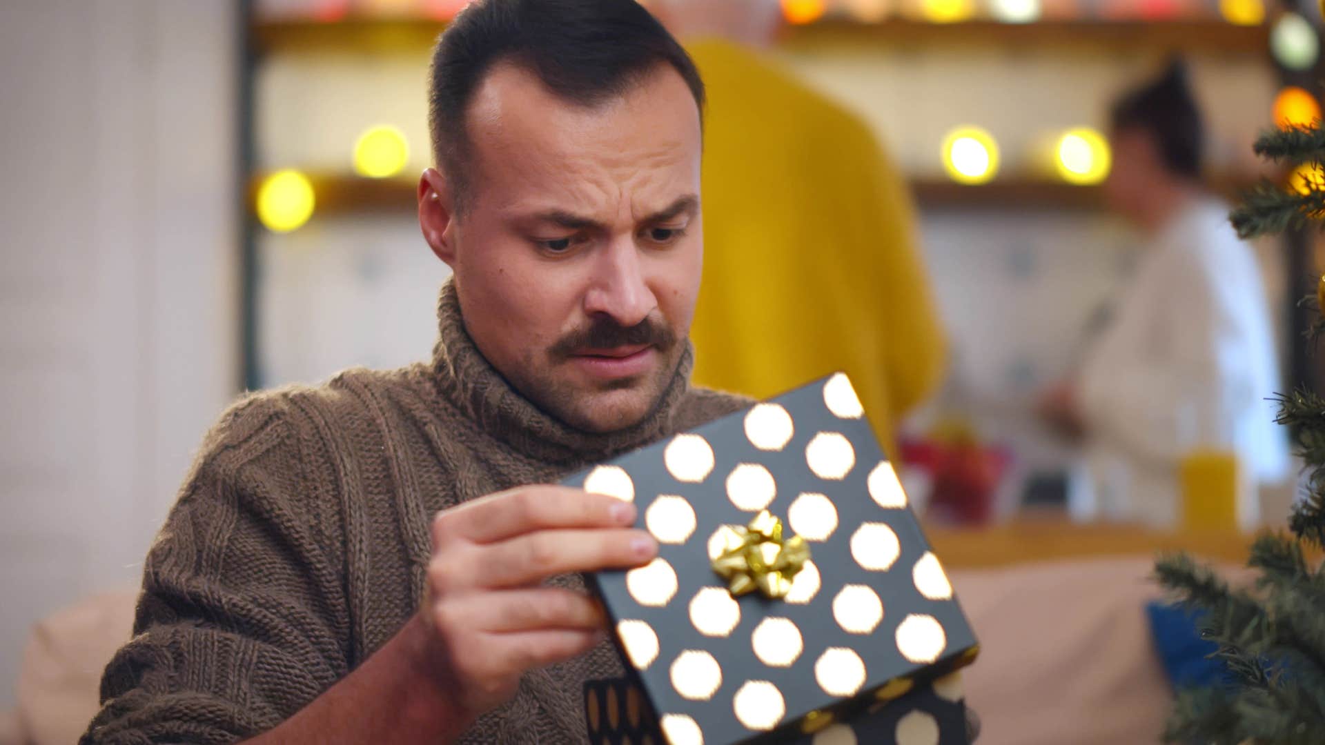 upset man opening gifts at home