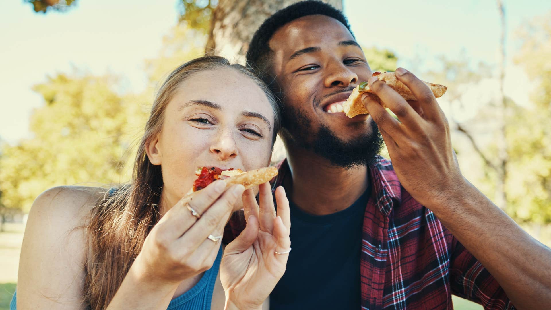 Couple smiling and eating fast food outside.