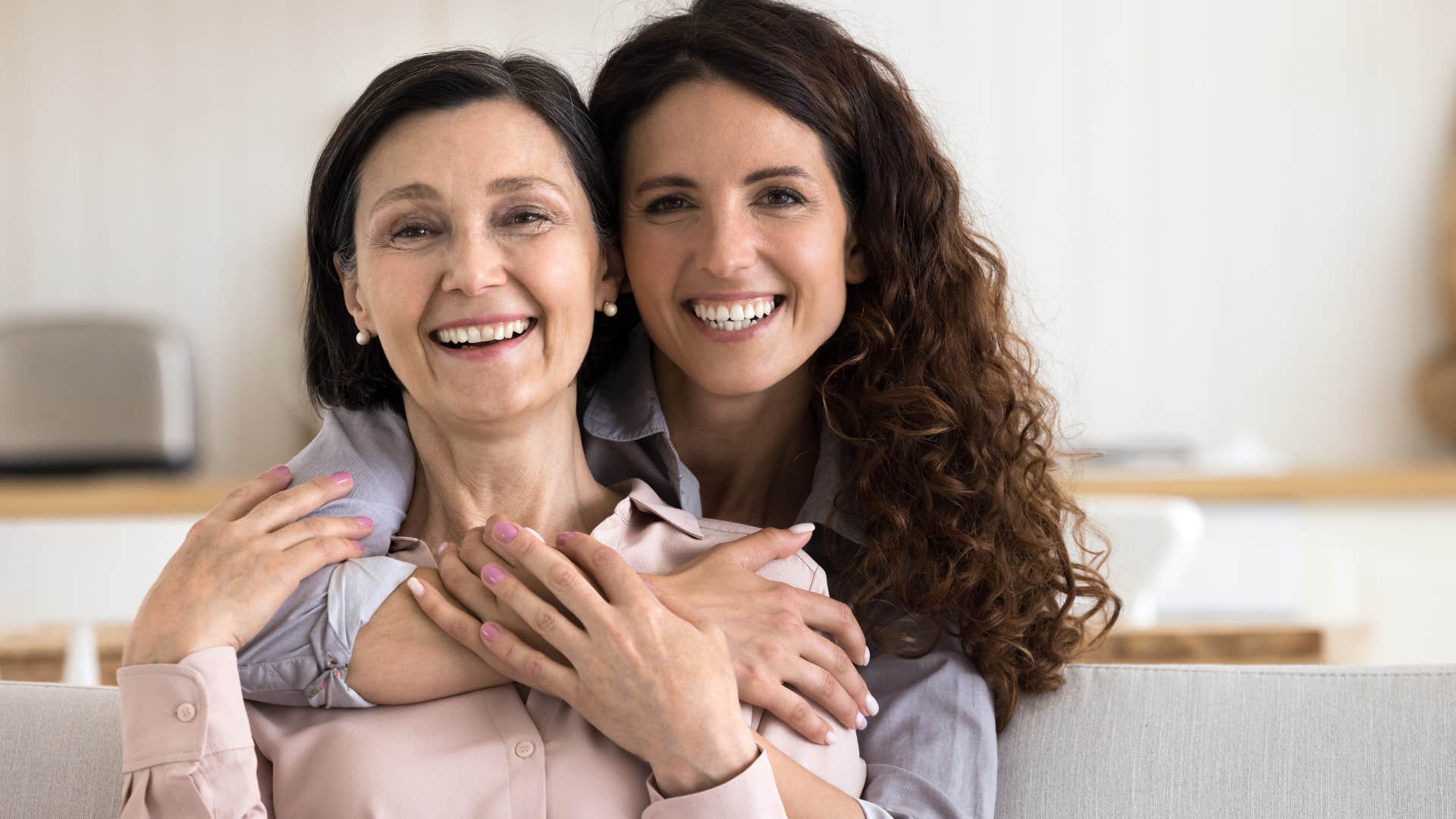 Woman who's living at home in adulthood hugging her mom.