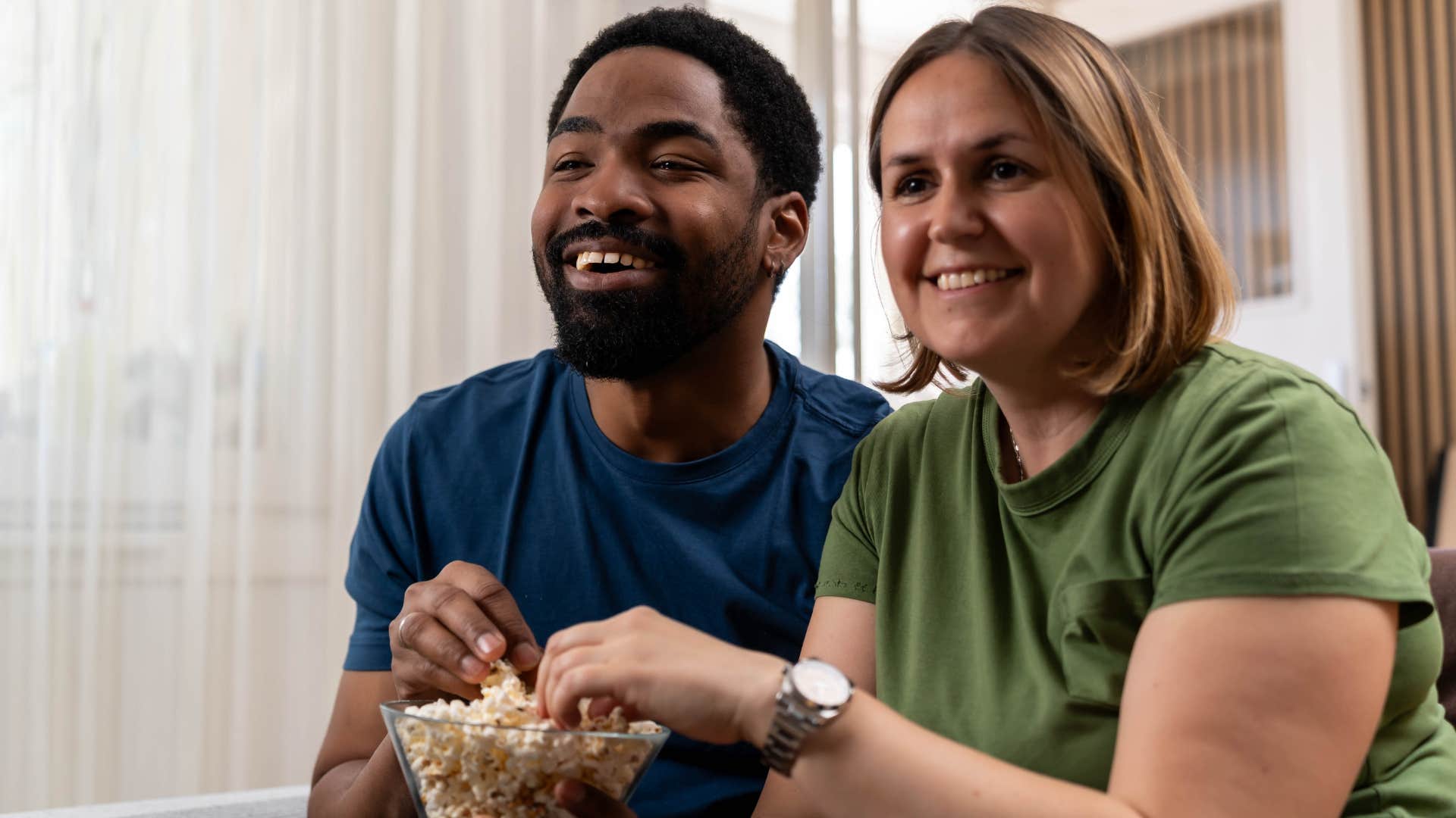 Couple smiling and watching TV at home.