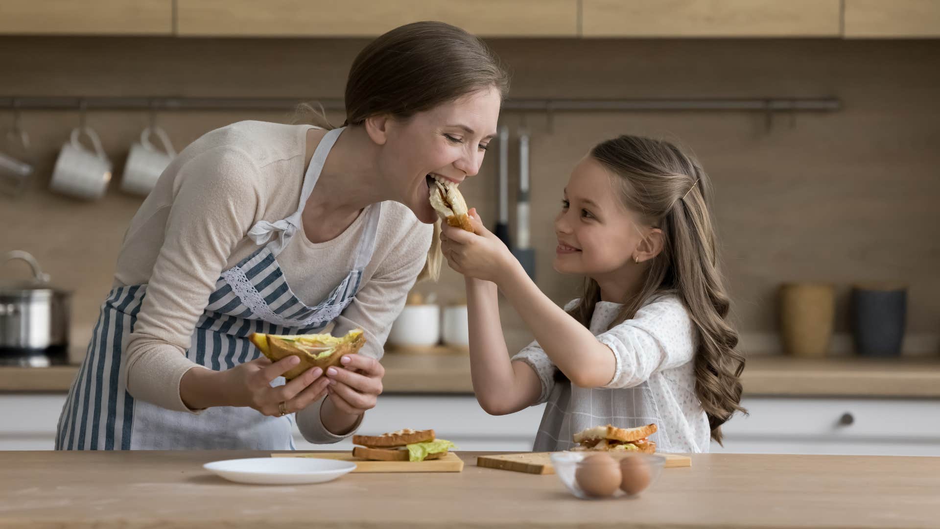 daughter feeding breakfast sandwich to mom