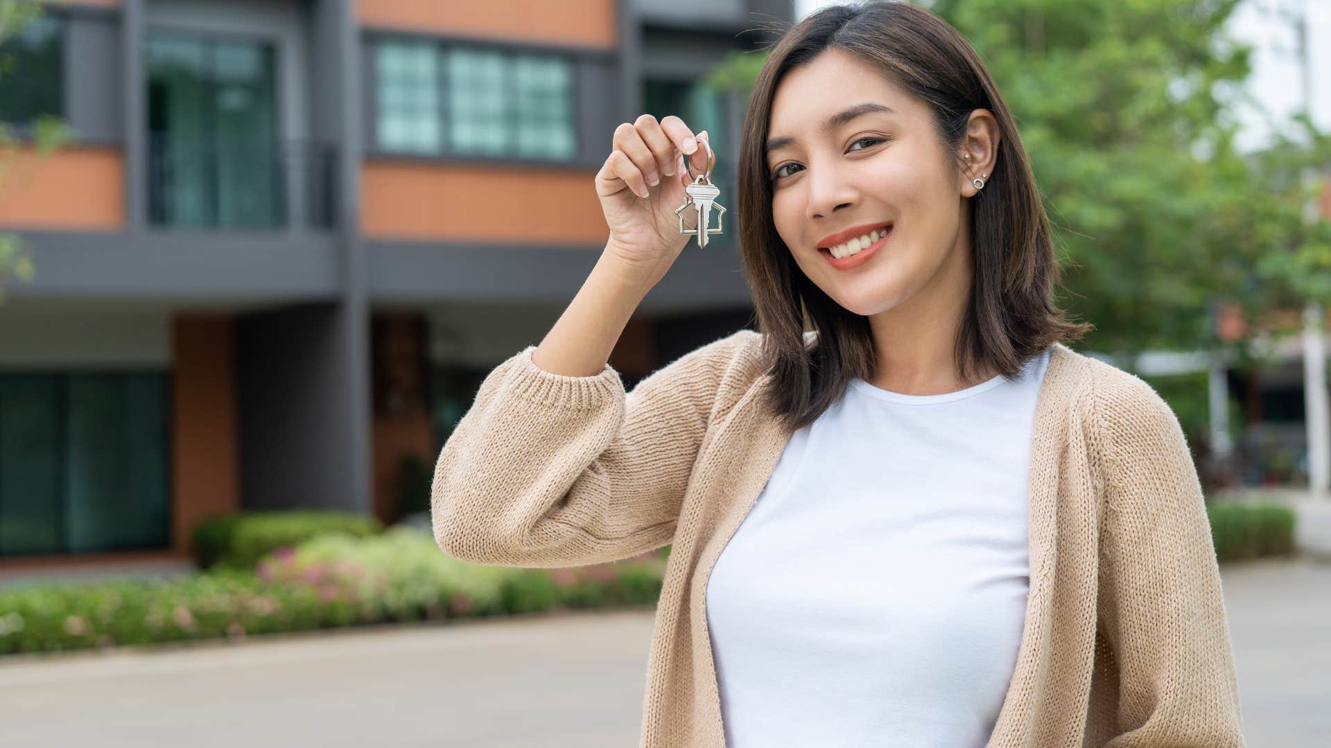 woman living beyond her means holding up house keys and saying it's an investment