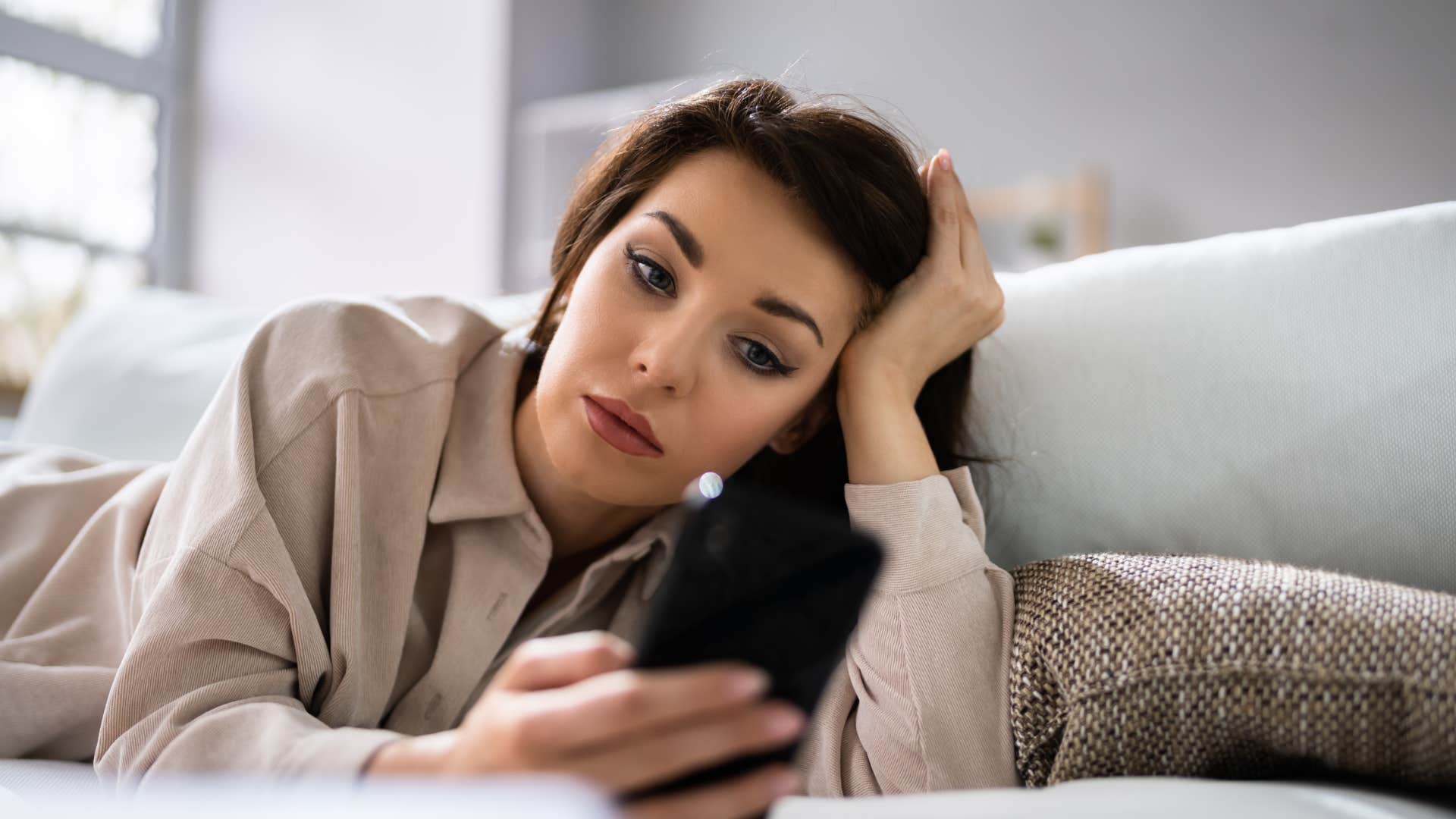woman checked out of her social life looking sad at her phone