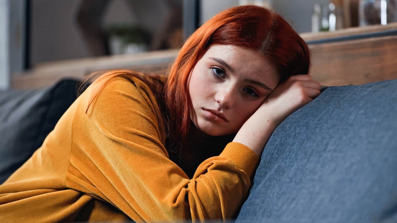 young woman emotionally checked out of her social life alone at home