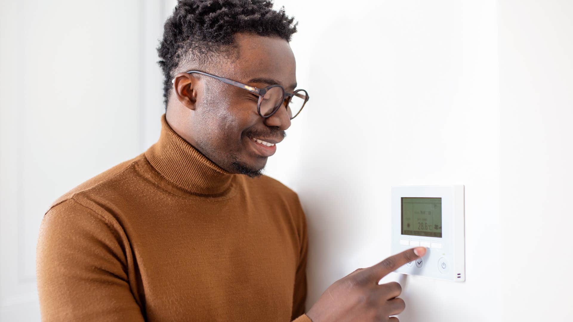man without a fireplace changing his thermostat