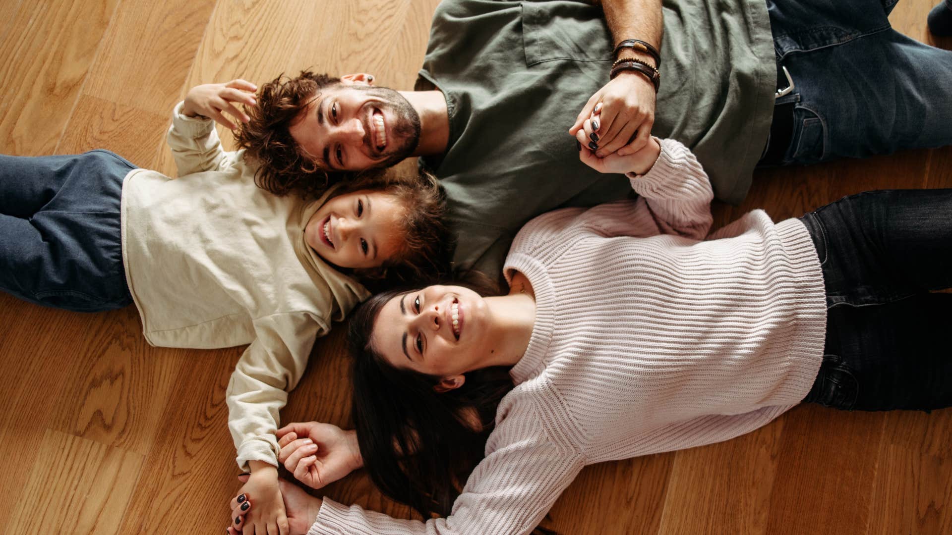 family laying down on hardwood floors