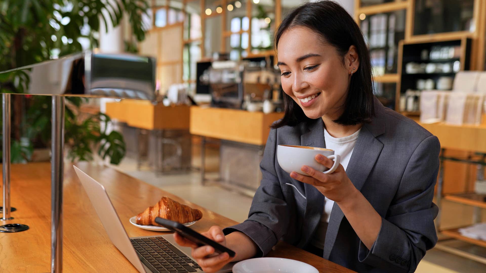 woman smiling and drinking coffee at a cafe