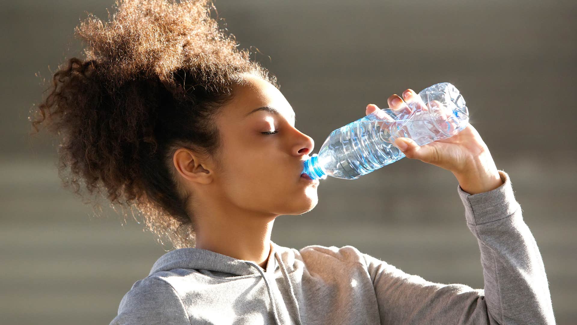 woman drinking from single-use water bottle