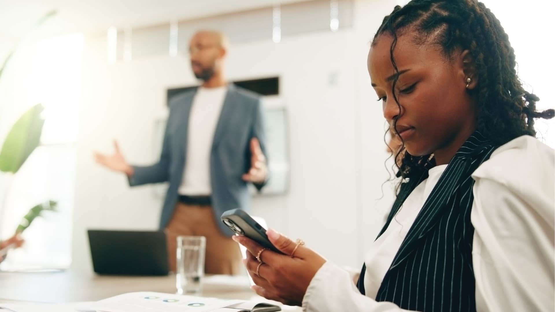 woman looking at her phone while colleague is speaking
