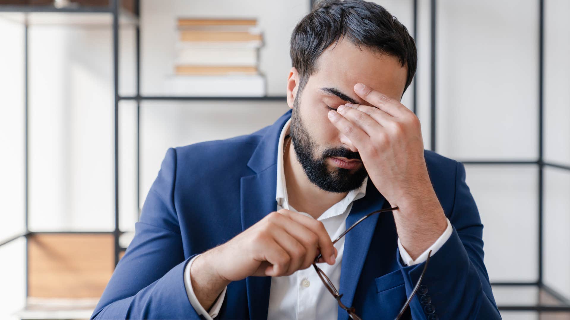 man holding his head stressed in a toxic workplace