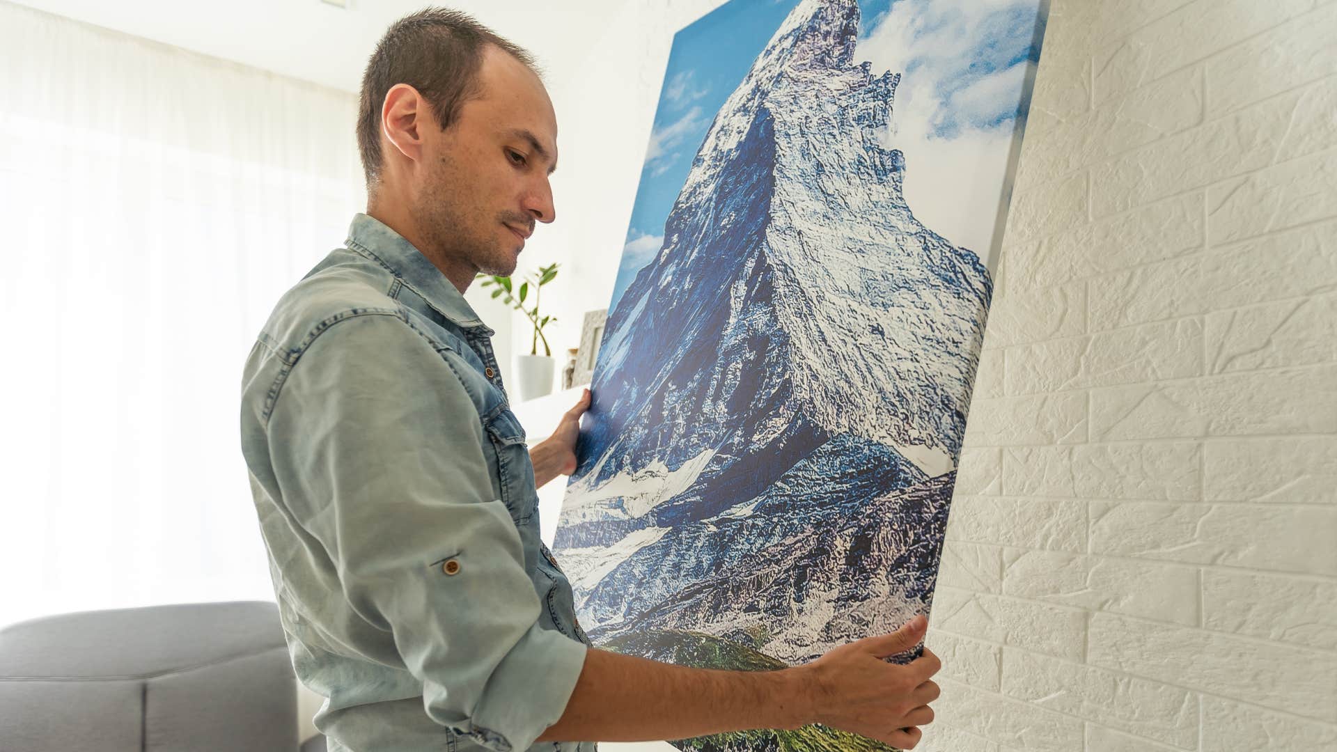 man hanging trendy artwork in his home
