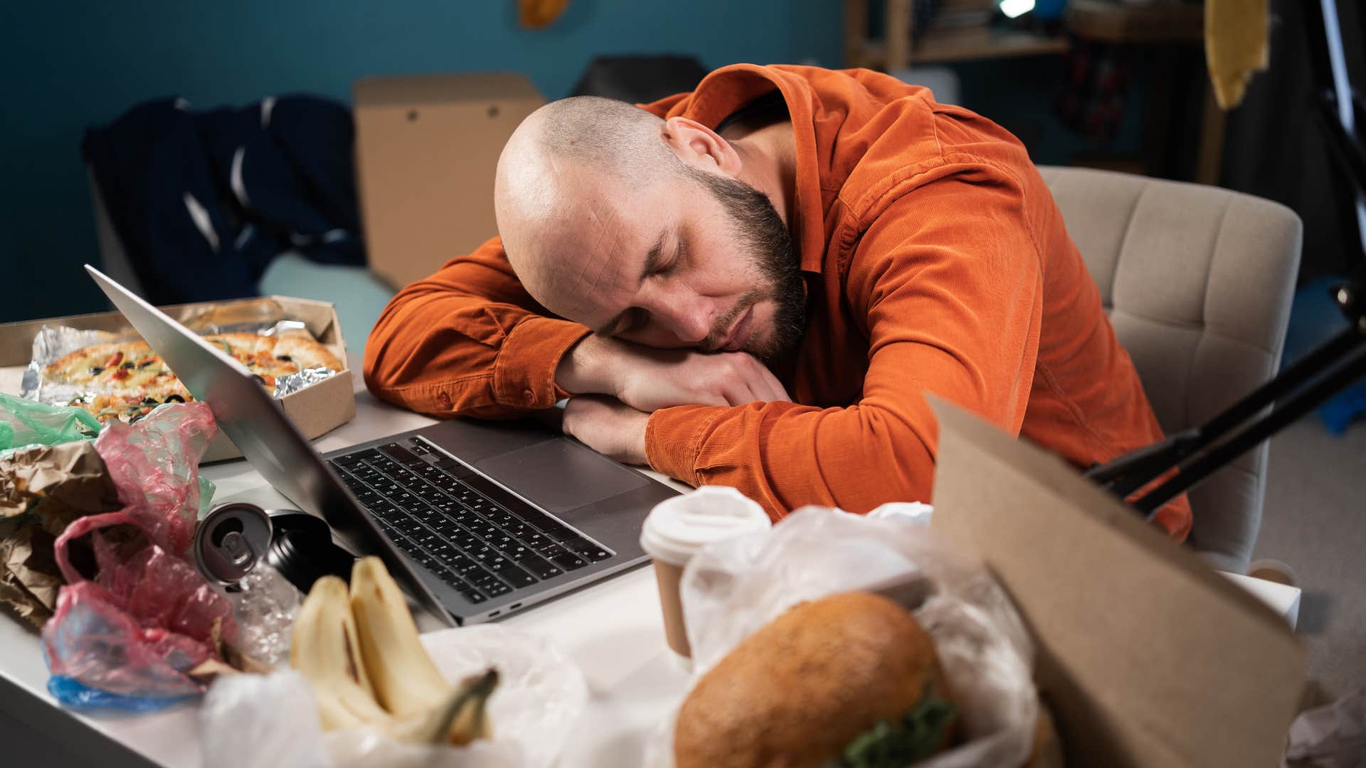 man asleep on a cluttered desk
