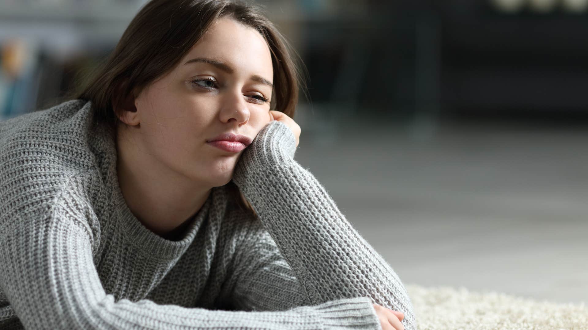 Bored woman thinking about laziness on the floor.