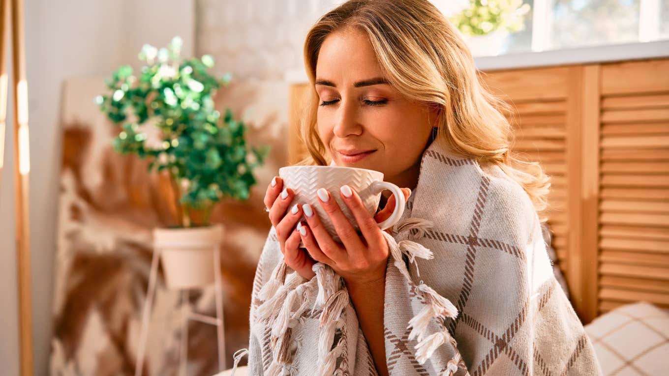 woman drinking out of cup in bed