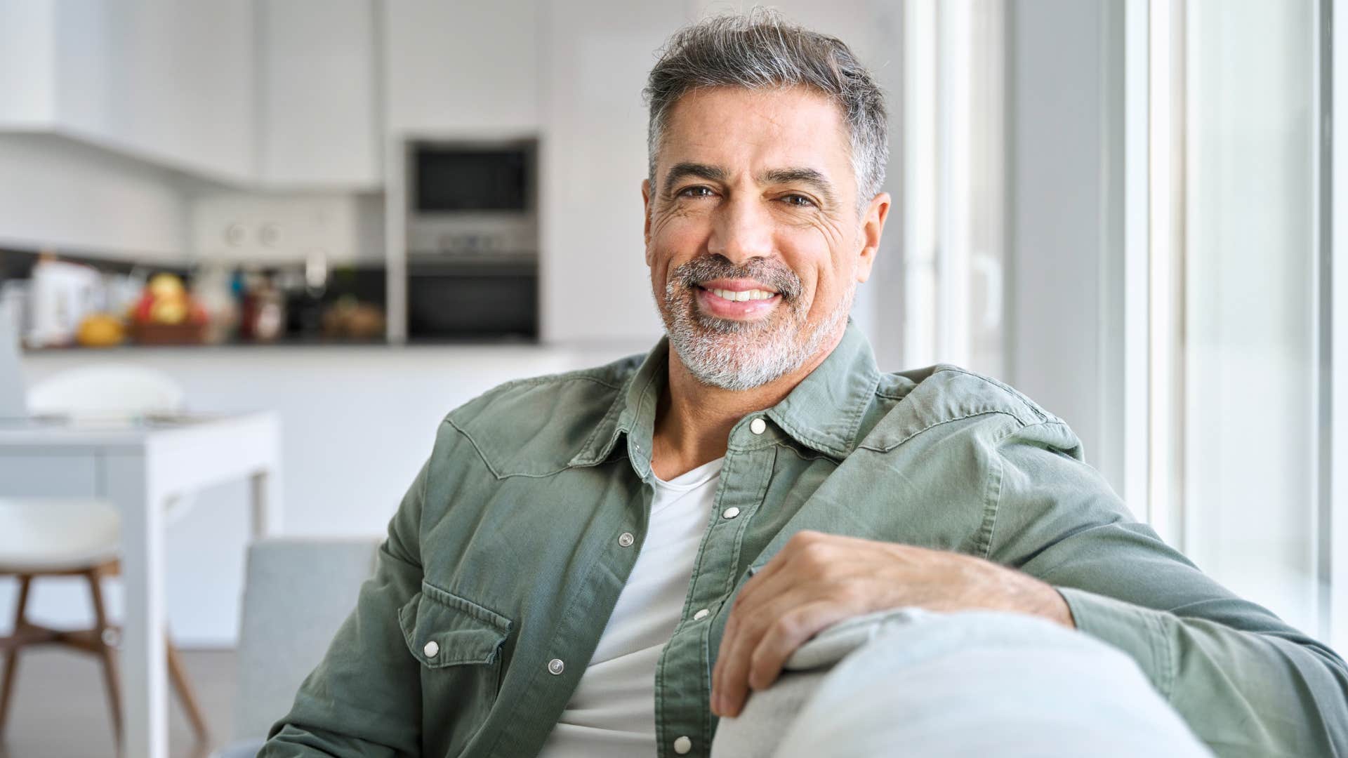 a wealthy man smiles while delivering his guest a mild insult