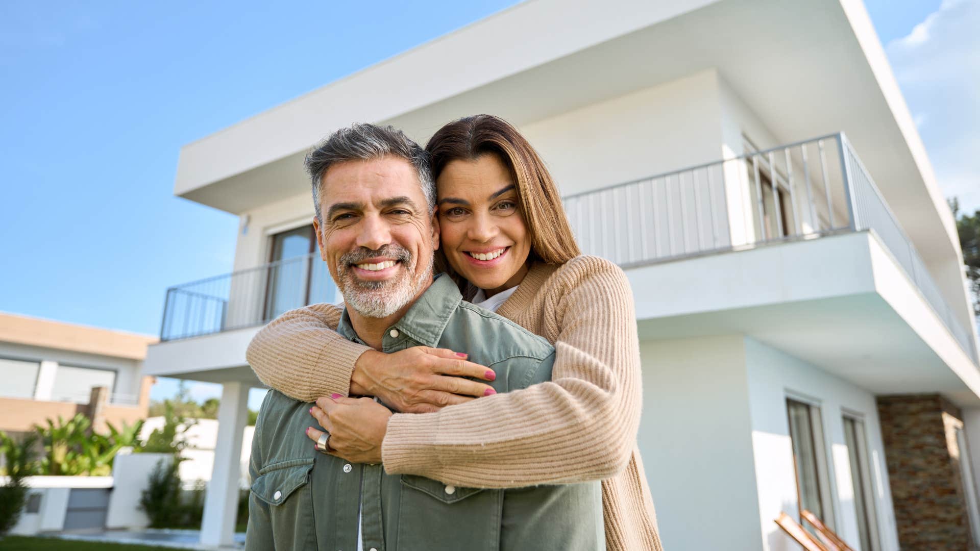 wealthy couple standing in front of their vacation home