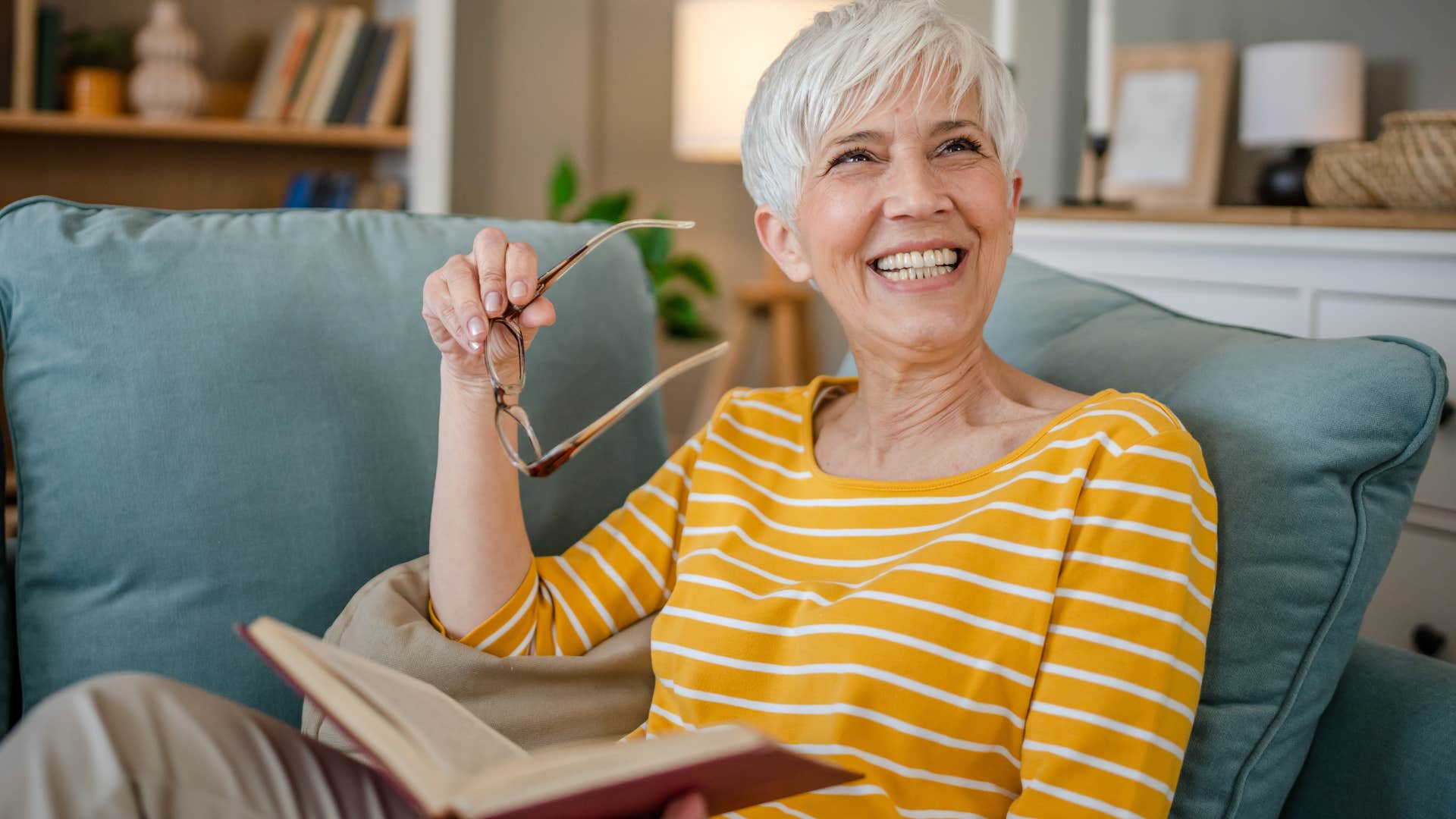 woman smiling reading a book with intentional furnishings in her home