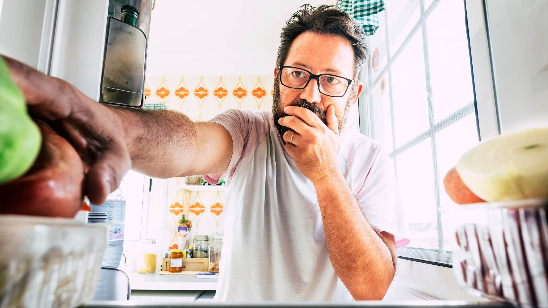 man grabbing expired food out of a fridge
