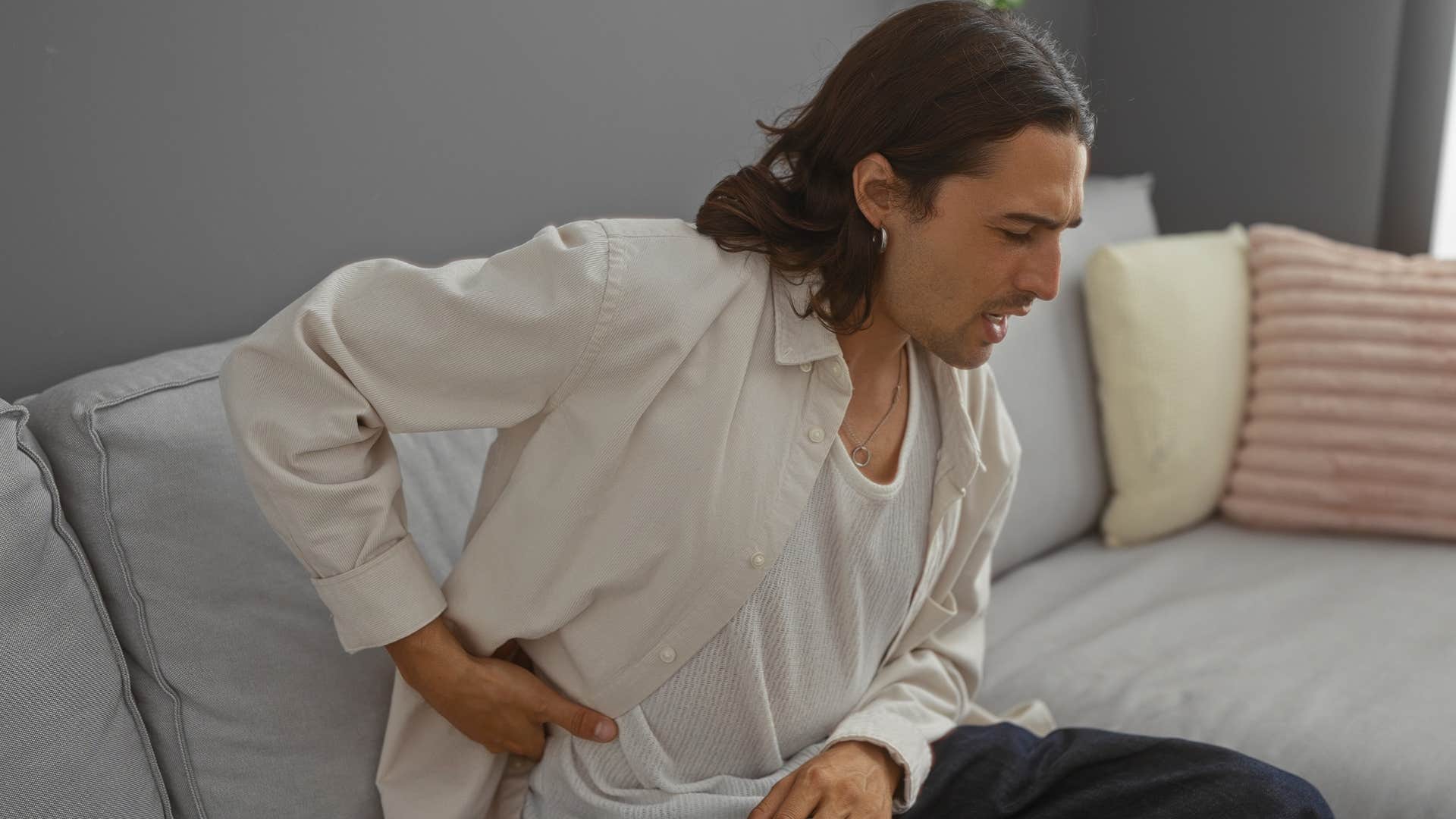 annoying man holding his back from trendy uncomfortable furniture