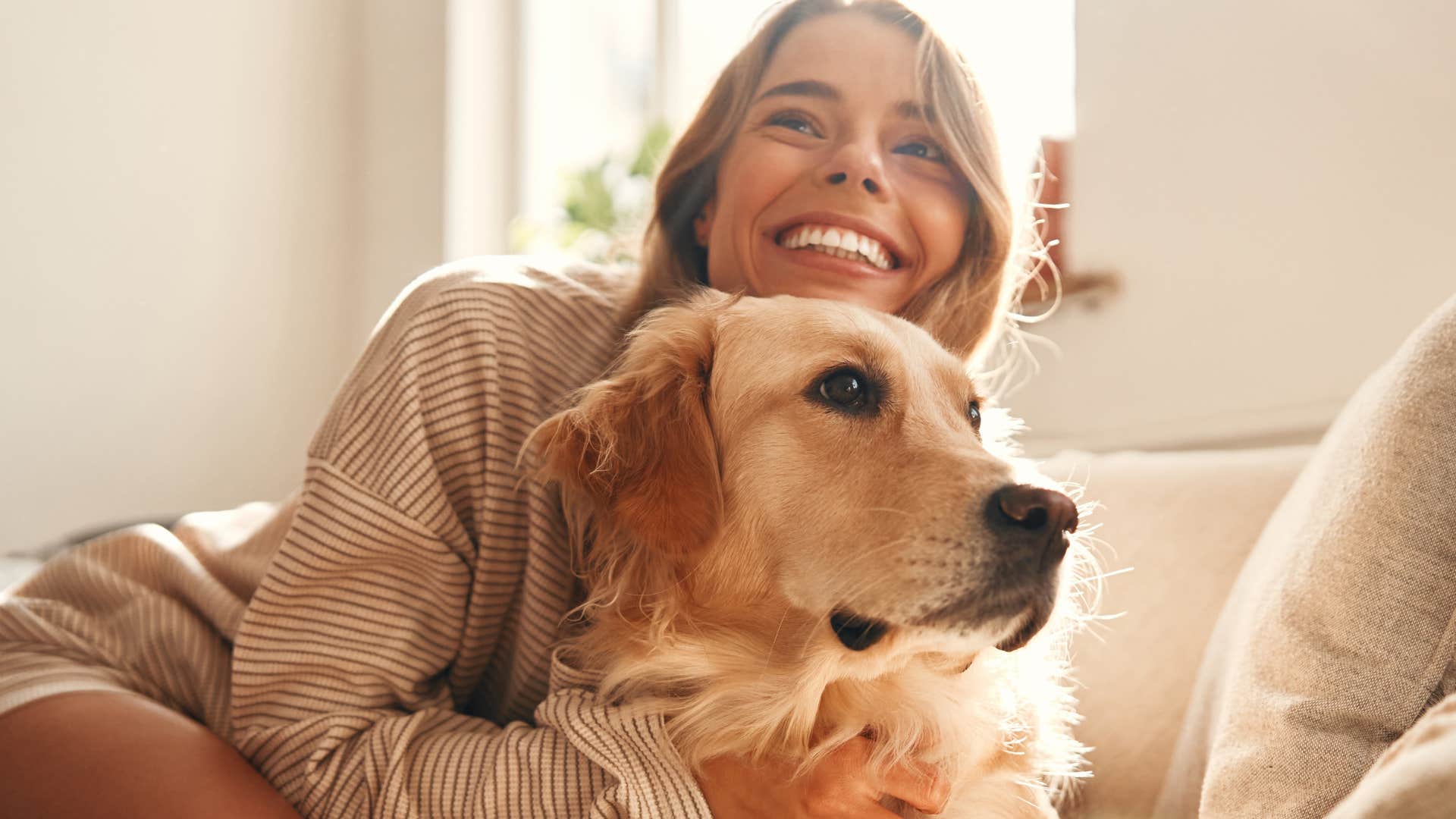 woman holding her untrained dog on the couch
