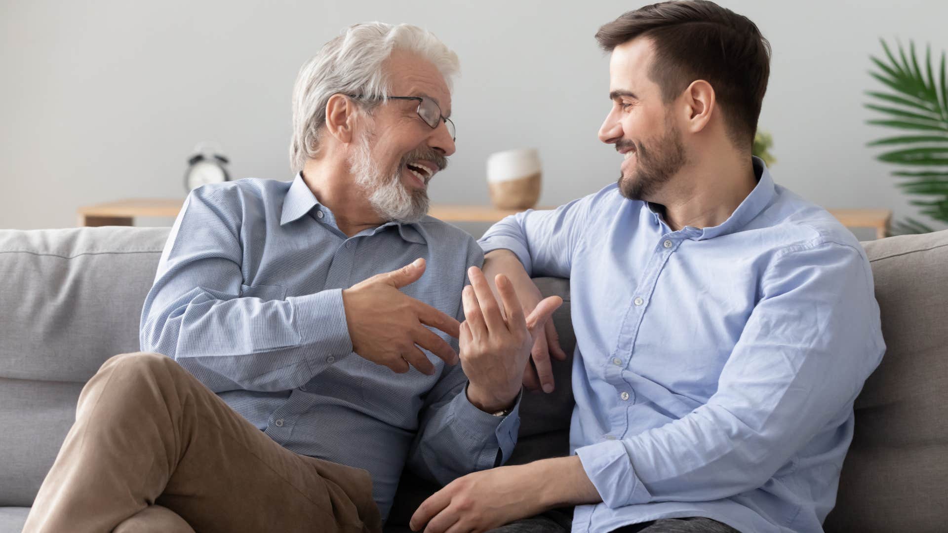 man and his adult son gossiping on the couch