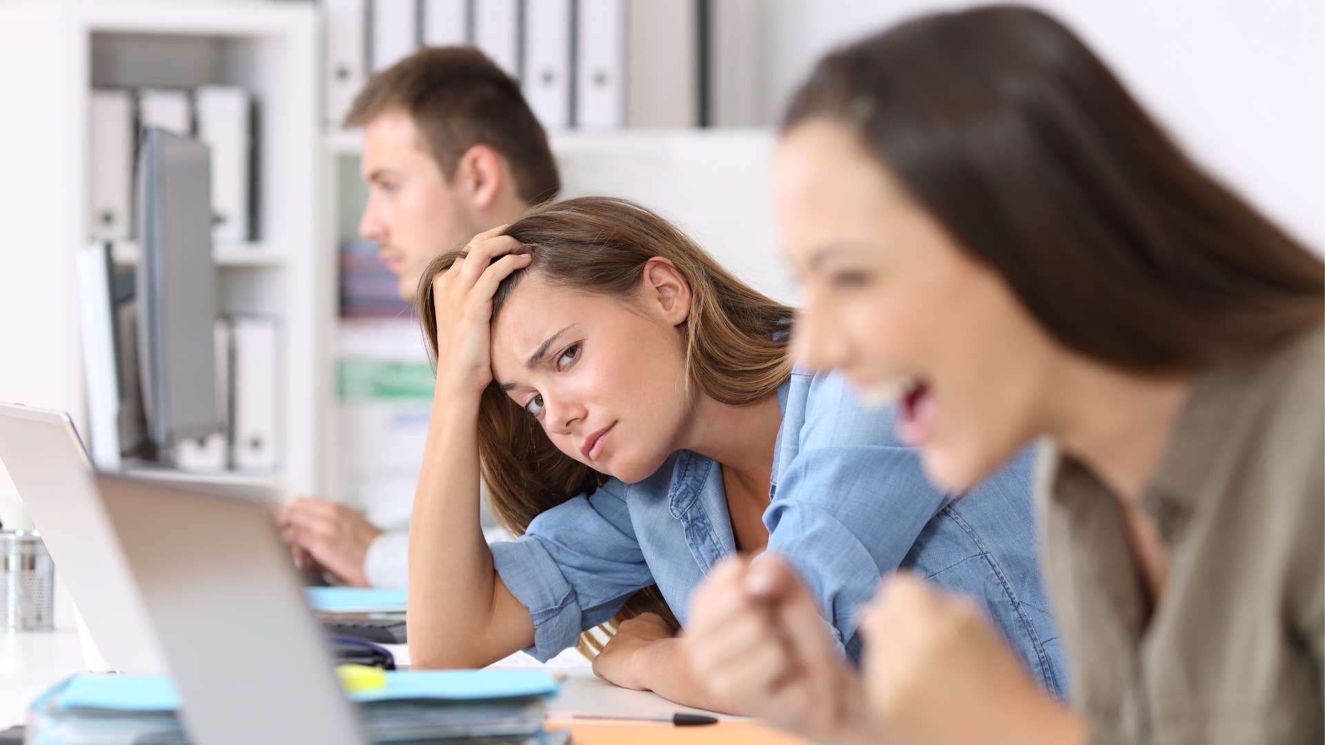 an unhappy woman keeps comparing herself to her coworker showing her jealousy