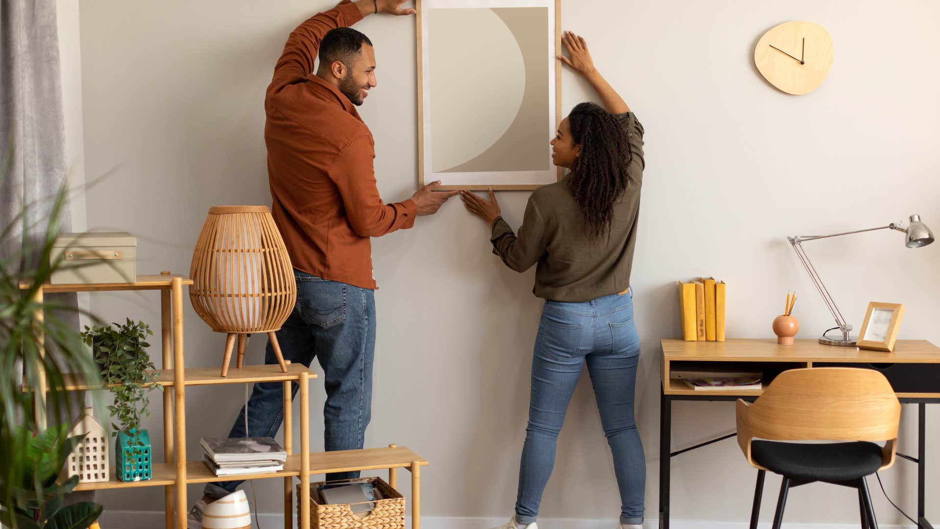 couple hanging up fine art painting at home