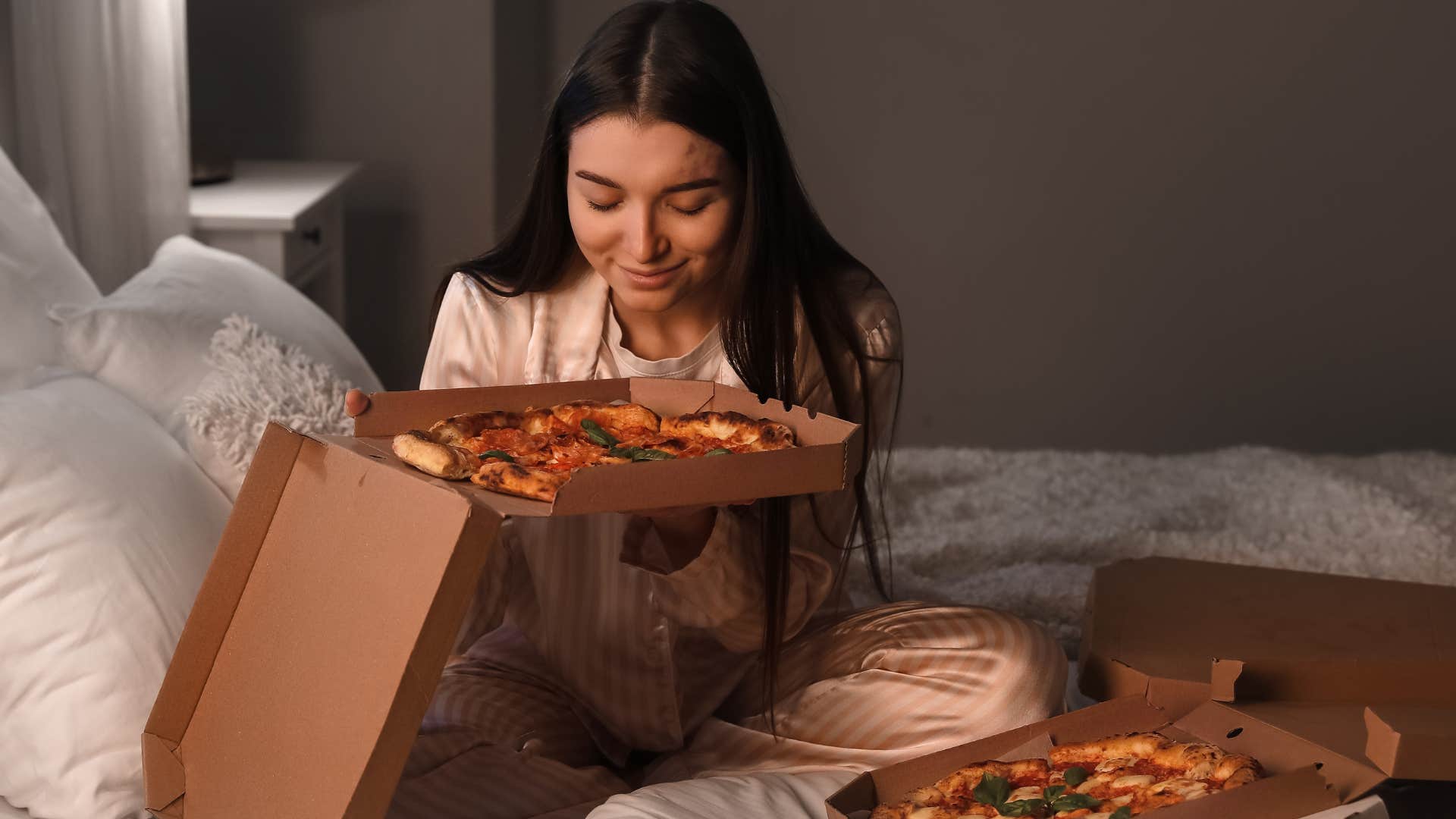 Woman eating processed foods in her bed.
