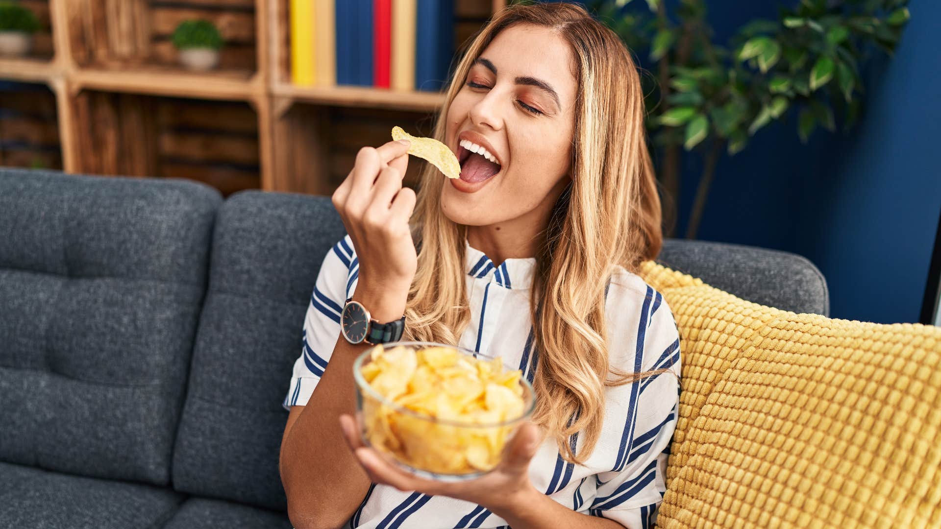 woman on couch eating junk food chips