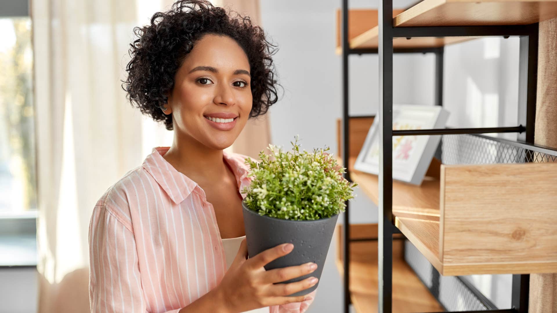 woman holding a plastic plant in her living room