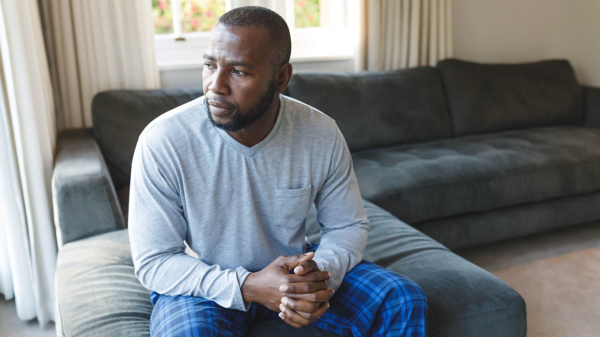 man sitting on uncomfortable couch at home