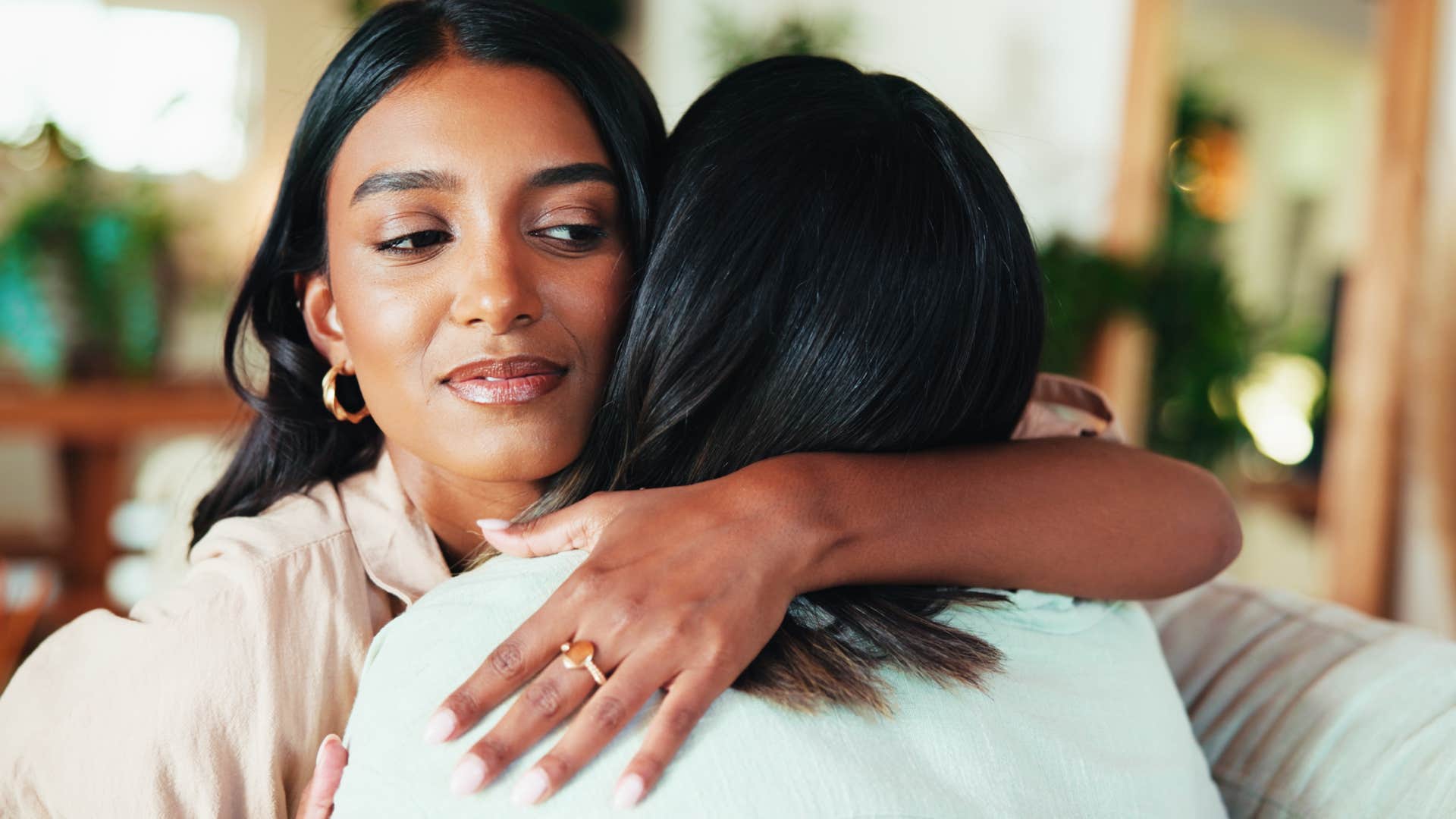 woman hugging her friend while gossiping behind her back