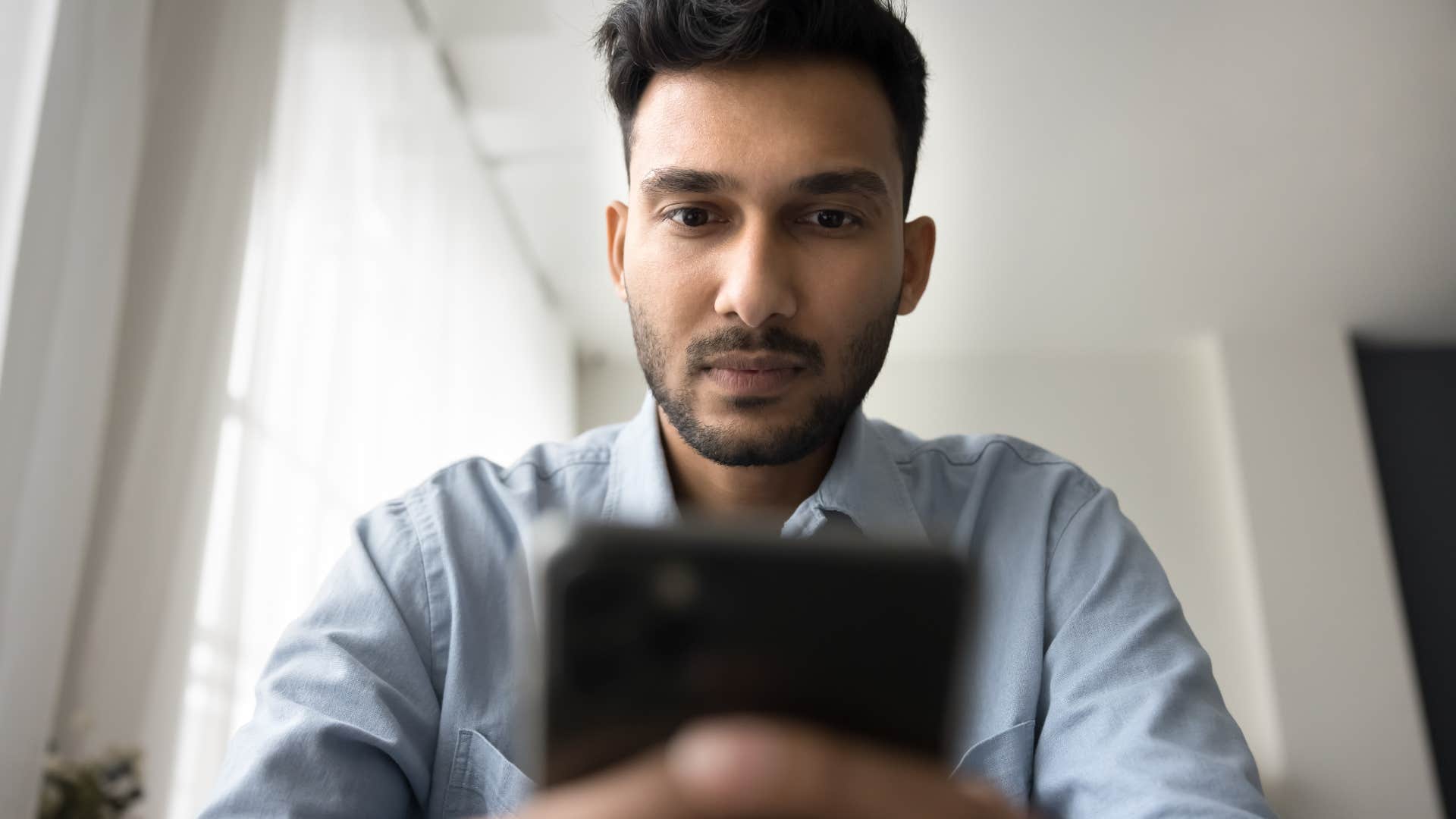 serious man looking at cash advances on his phone