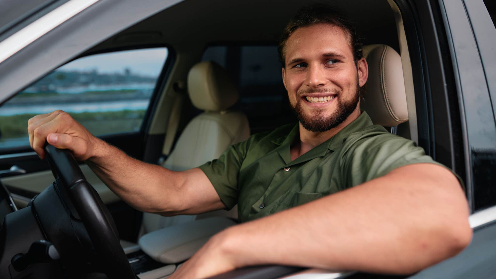 man driving a brand new car and smiling
